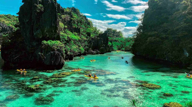 Tourists kayaking on crystal clear lagoon in El Nido, Palawan